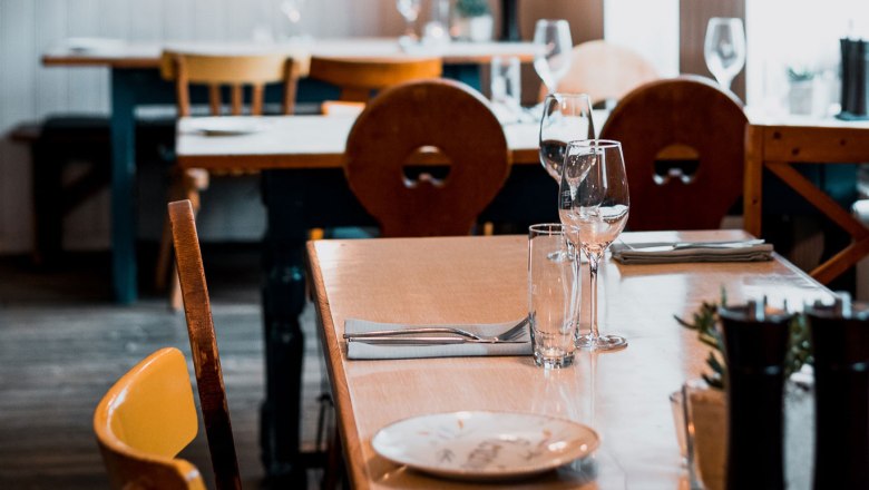 Egy hangulatos étteremben megterített asztal, fabútorokkal és borospoharakkal.