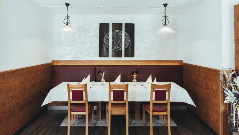 Stílusosan megterített asztal egy étteremben, amelynek falán faburkolat és modern művészeti alkotások láthatók.