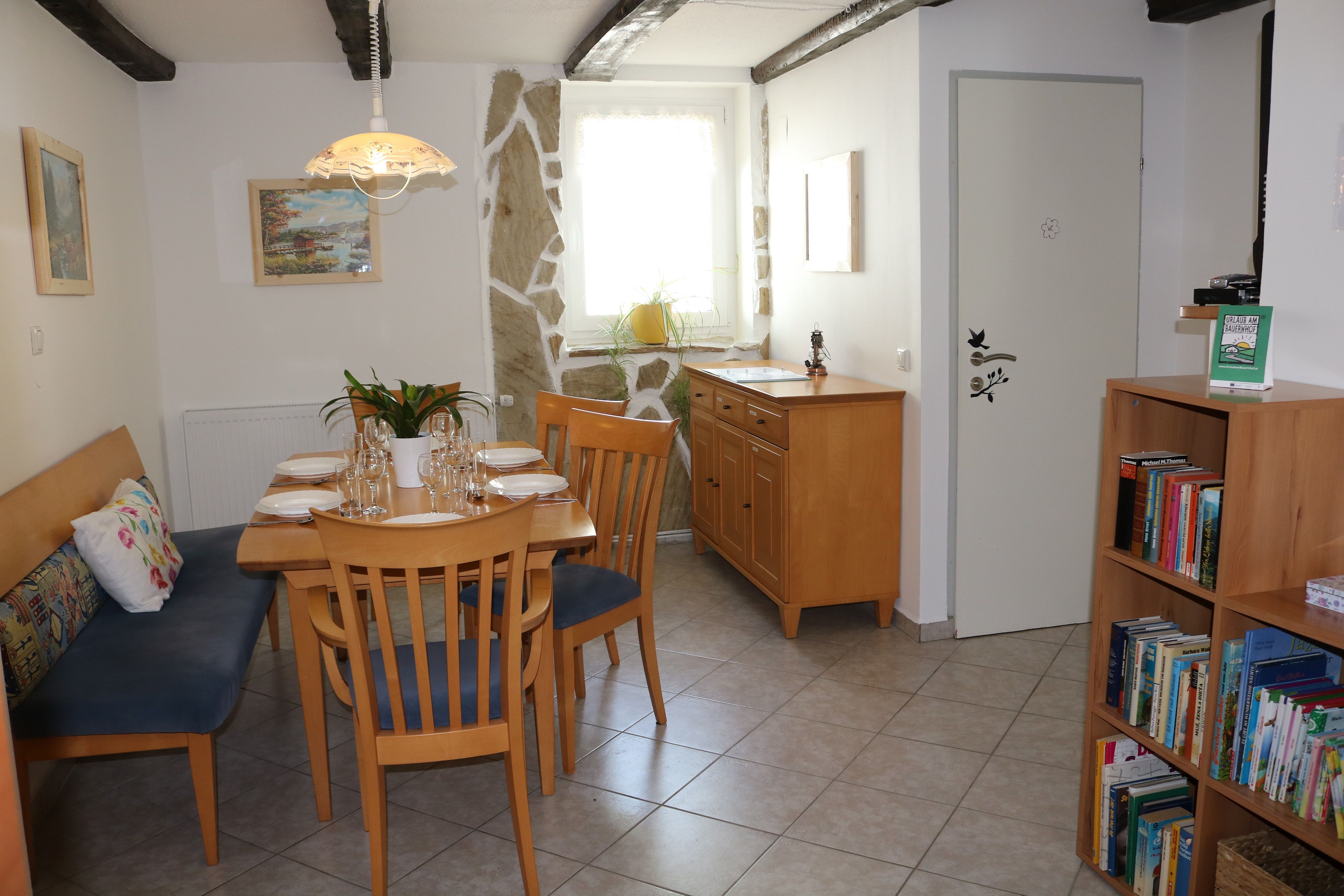 Étkező fából készült asztallal, székekkel és könyvespolccal.