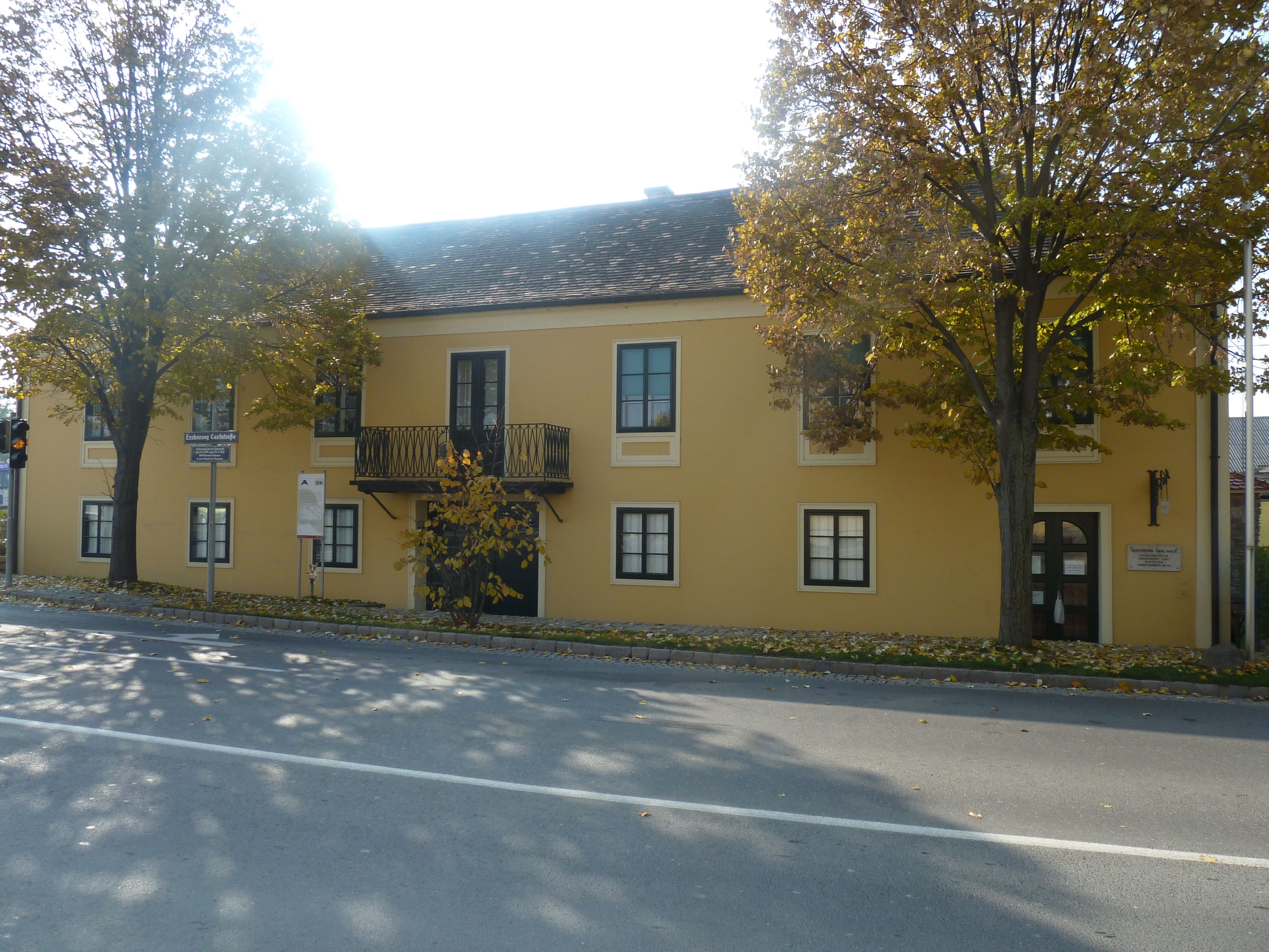 Sárga épület erkéllyel és előtte fákkal, Carl főherceg háza és Napóleon Múzeum Deutsch-Wagramban.