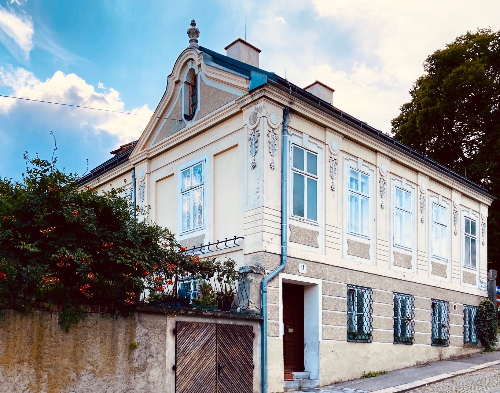 Egy történelmi villa külső nézete díszes ablakokkal és nyeregtetővel.