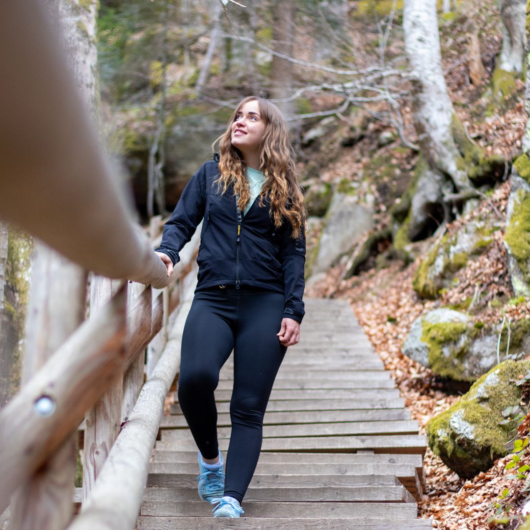 Egy nő sétál egy falépcsőn egy erdős területen.