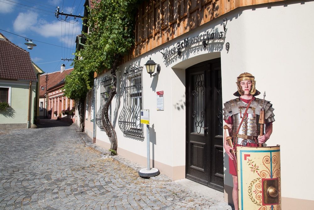 Egy római katonát ábrázoló kartonlap áll egy épület előtt Traismauerben.