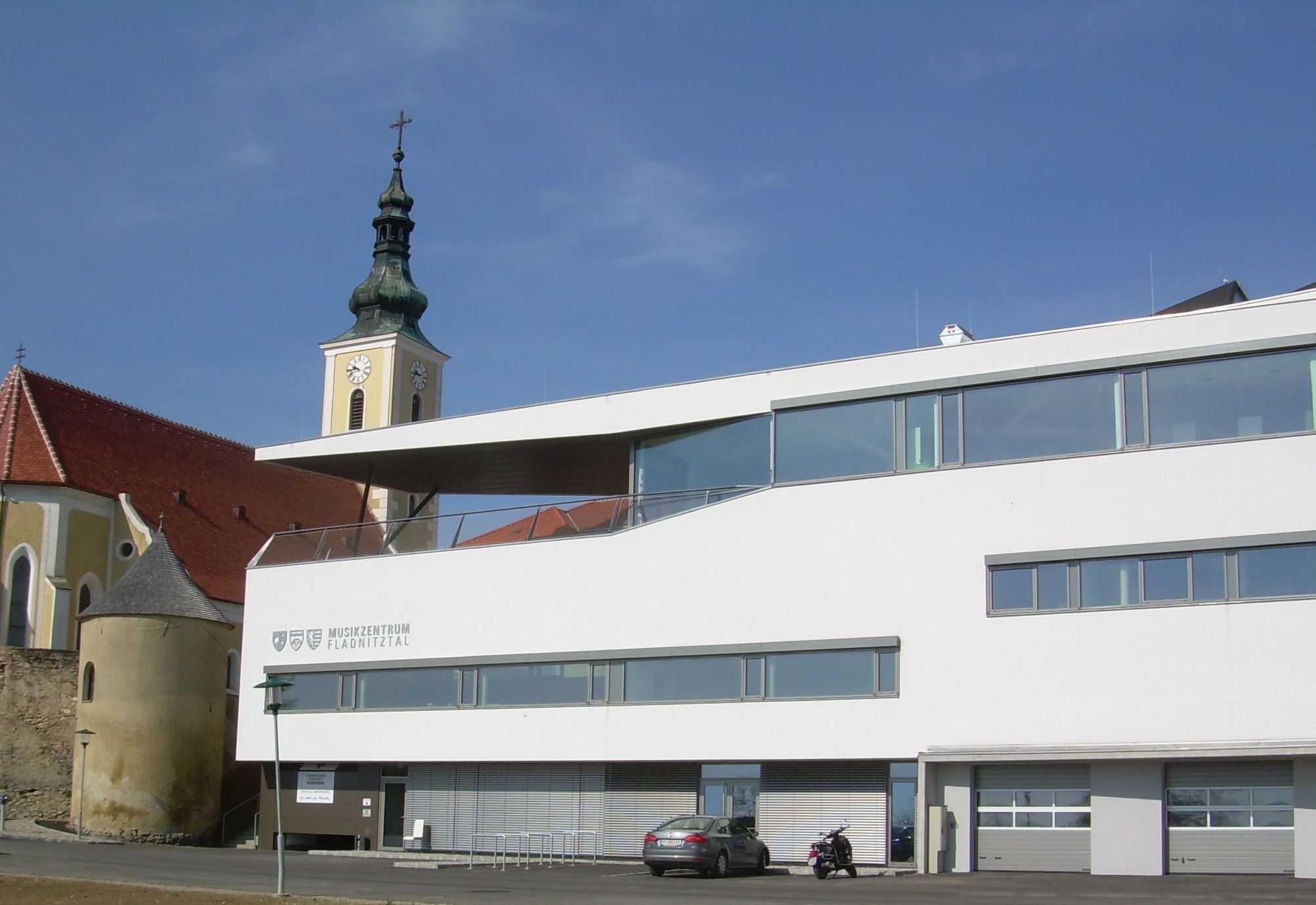 Modern épület a templomtoronnyal a háttérben Wölblingben.
