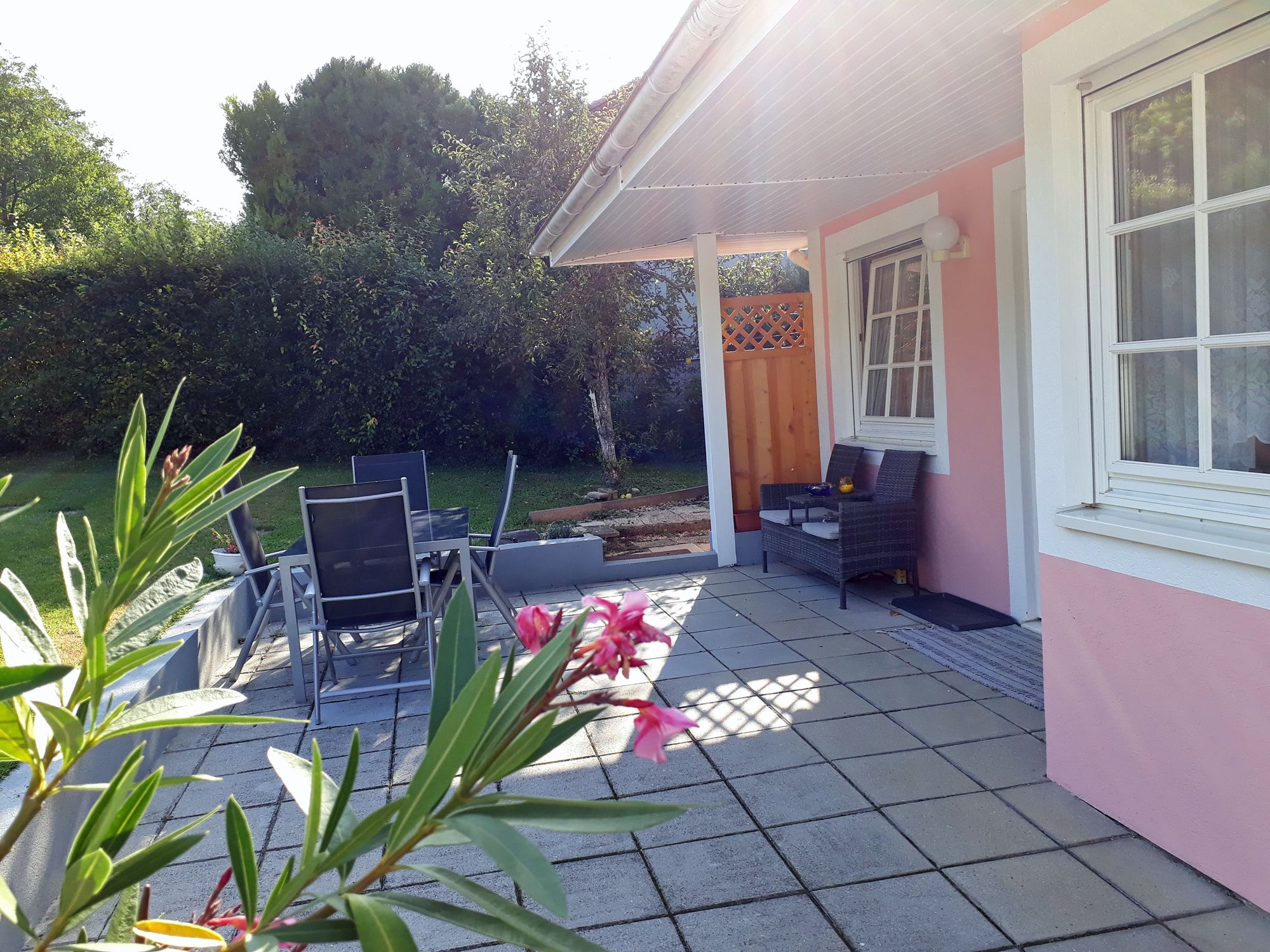 Terasz kerti bútorokkal és rózsaszín ház homlokzattal.