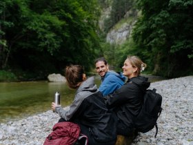 drei Wander:innen sitzen am Fluss im H&ouml;llental, &copy; N&Ouml;W_Robin Uthe