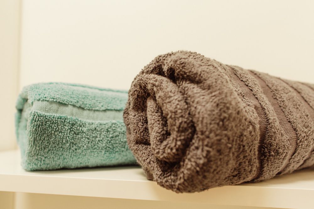 Két törülköző, egy türkizkék és egy barna, fekszik a polcon.