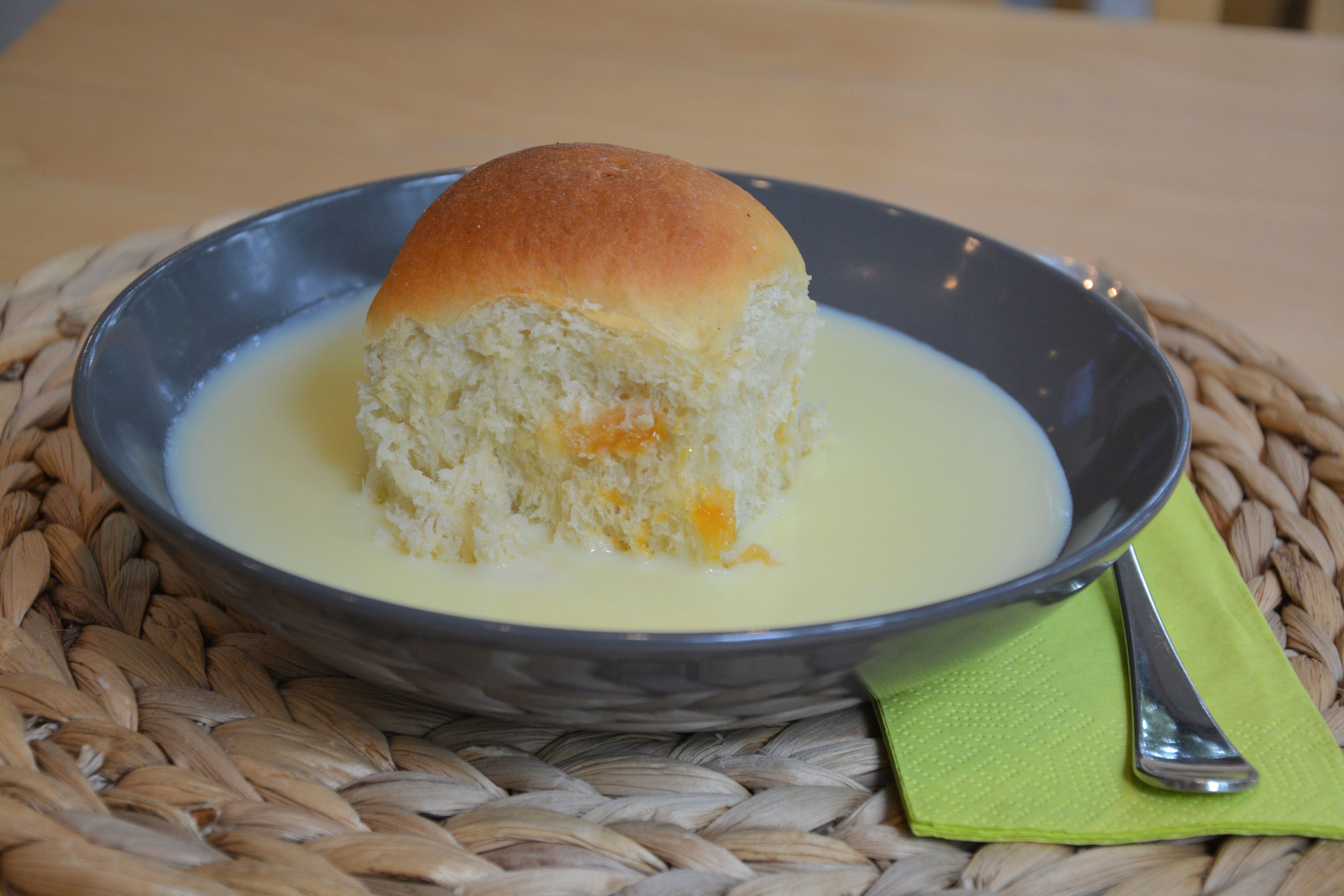 Egy fekete tányér, rajta sütemény és vaníliaszósz, mellette egy zöld szalvéta villával.