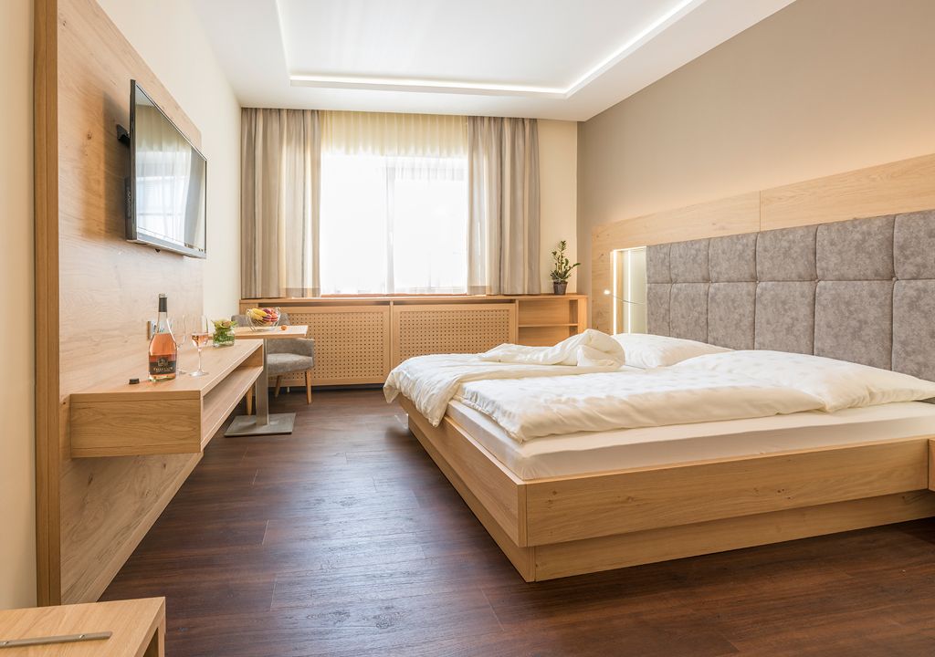Modern vendégszoba franciaággyal, síkképernyős TV-vel és fabútorokkal.