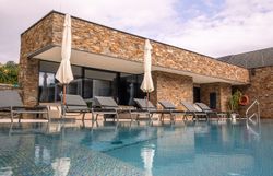 Egy modern szálloda külső nézete medencével és nyugágyakkal.