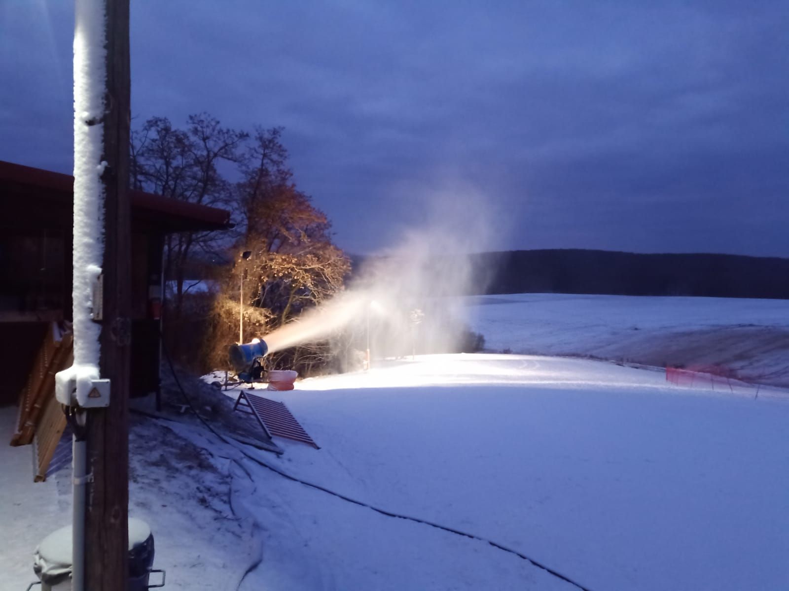 Hóágyú havat gyárt a pályán alkonyatkor.