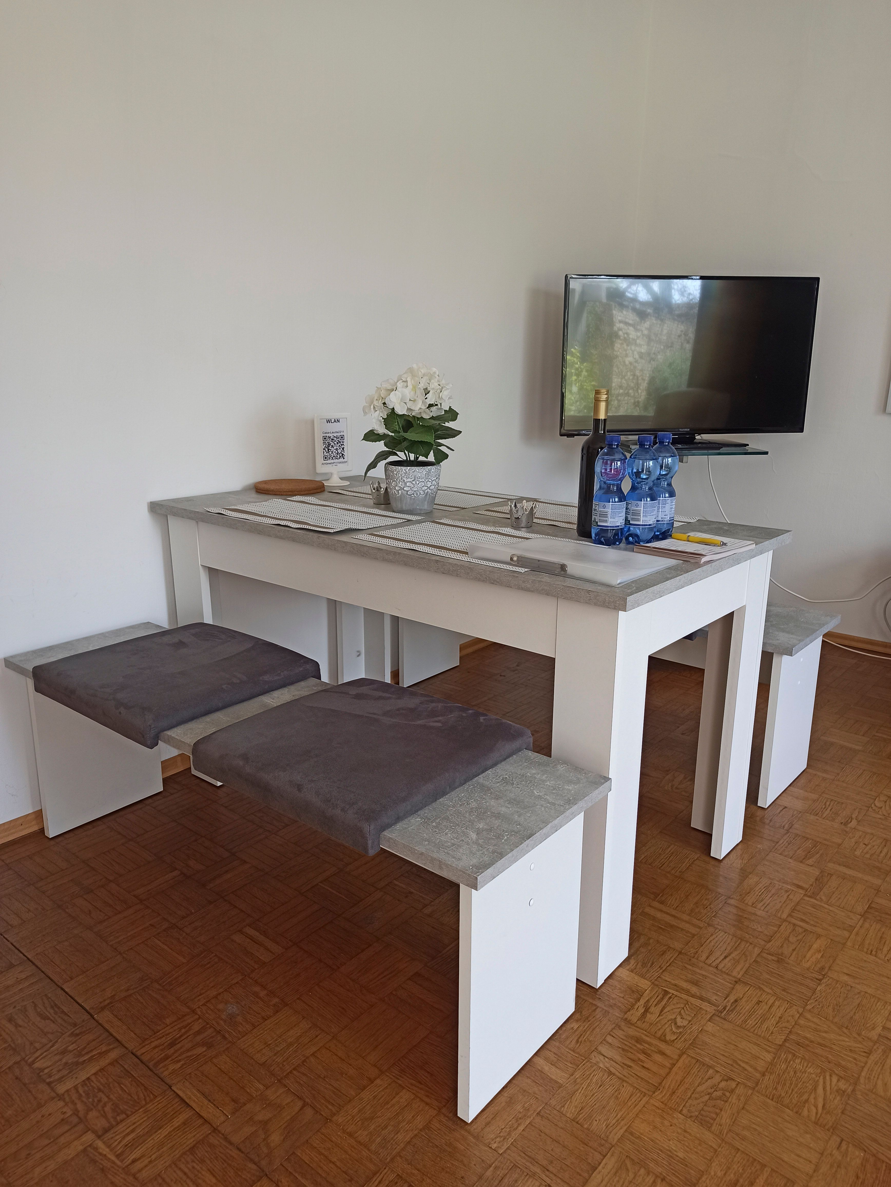 Modern társalgó asztalokkal, padokkal, TV-vel és dekorációval.