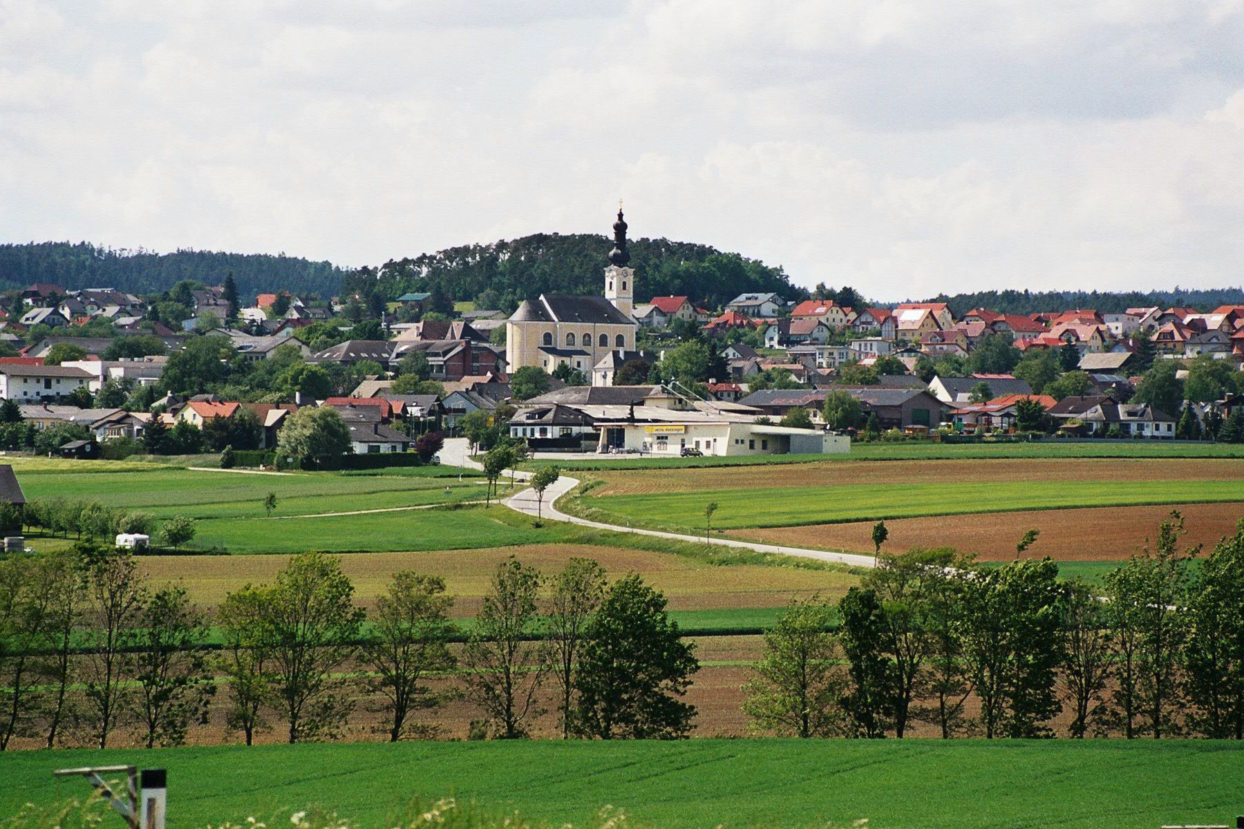 Karlstetten mezővárosának panorámája a templommal és a környező mezőkkel.