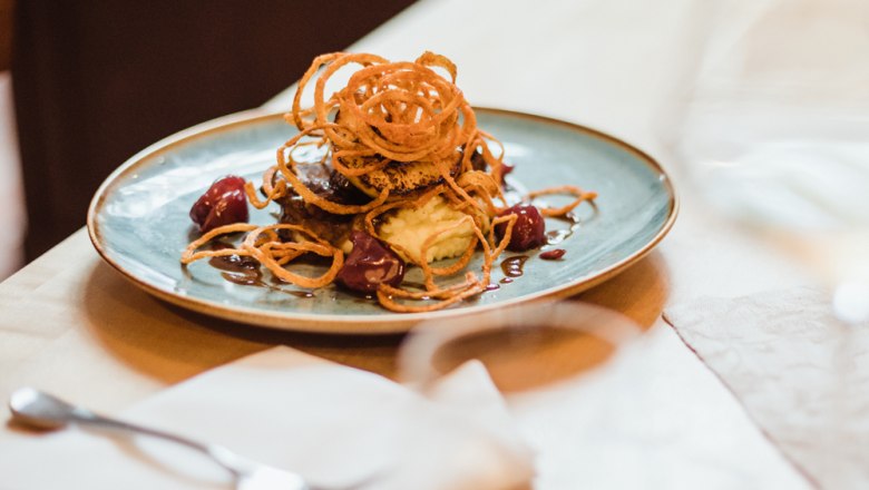 Húsétel hagymakarikákkal, burgonyapürével és mártással.