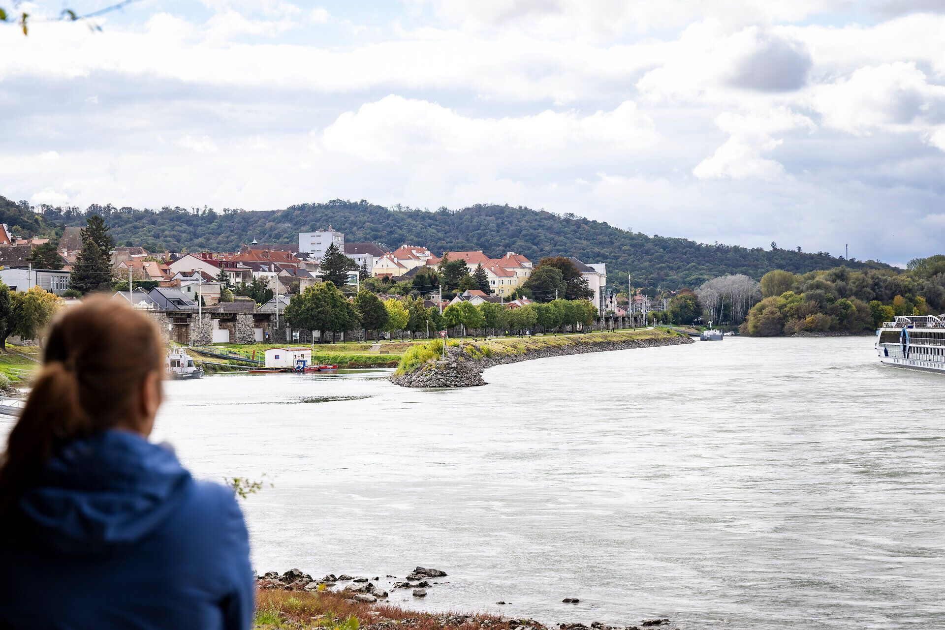 Egy nő nézi a Dunát és Hainburg házait a Duna partján.