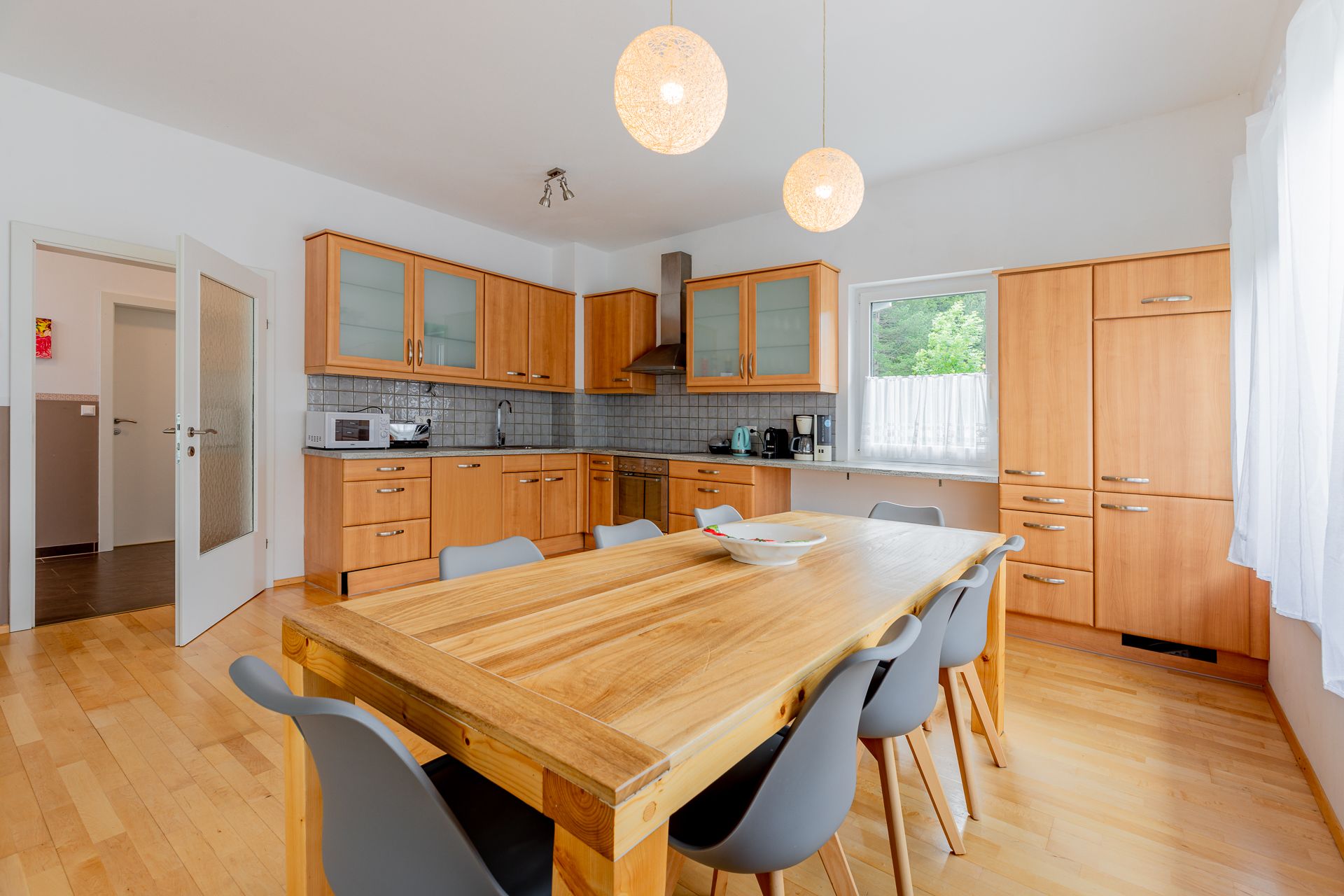 Modern konyha fa bútorokkal és nagy étkezőasztallal.