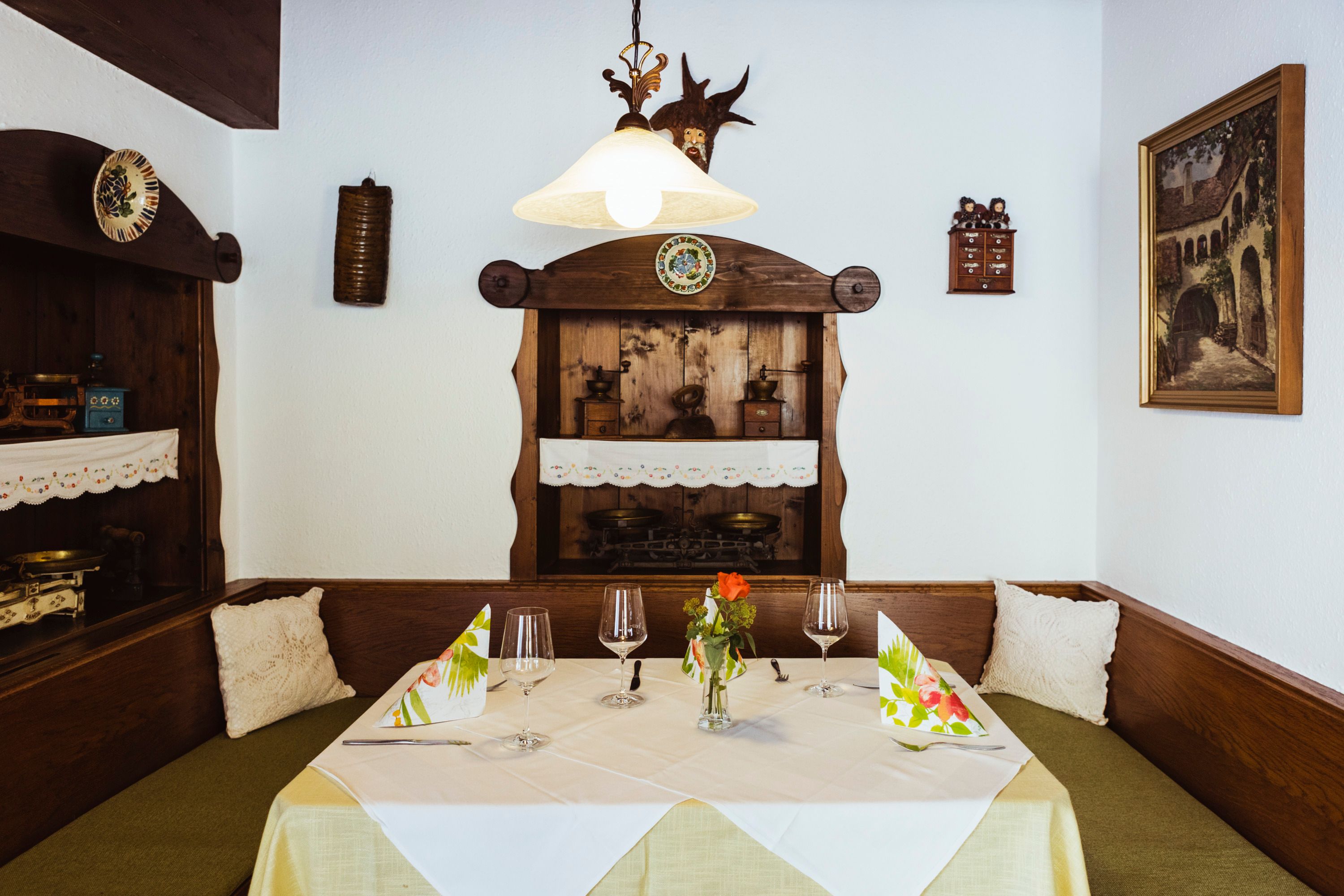 Hangulatos ülőhely egy étteremben, fabútorokkal, dekoratív részletekkel és terítékkel.