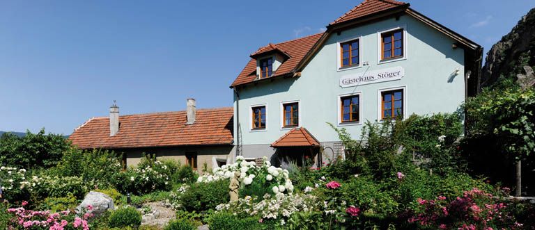 Egy hagyományos ház kerttel, a "Gasthaus Stöger" felirattal.