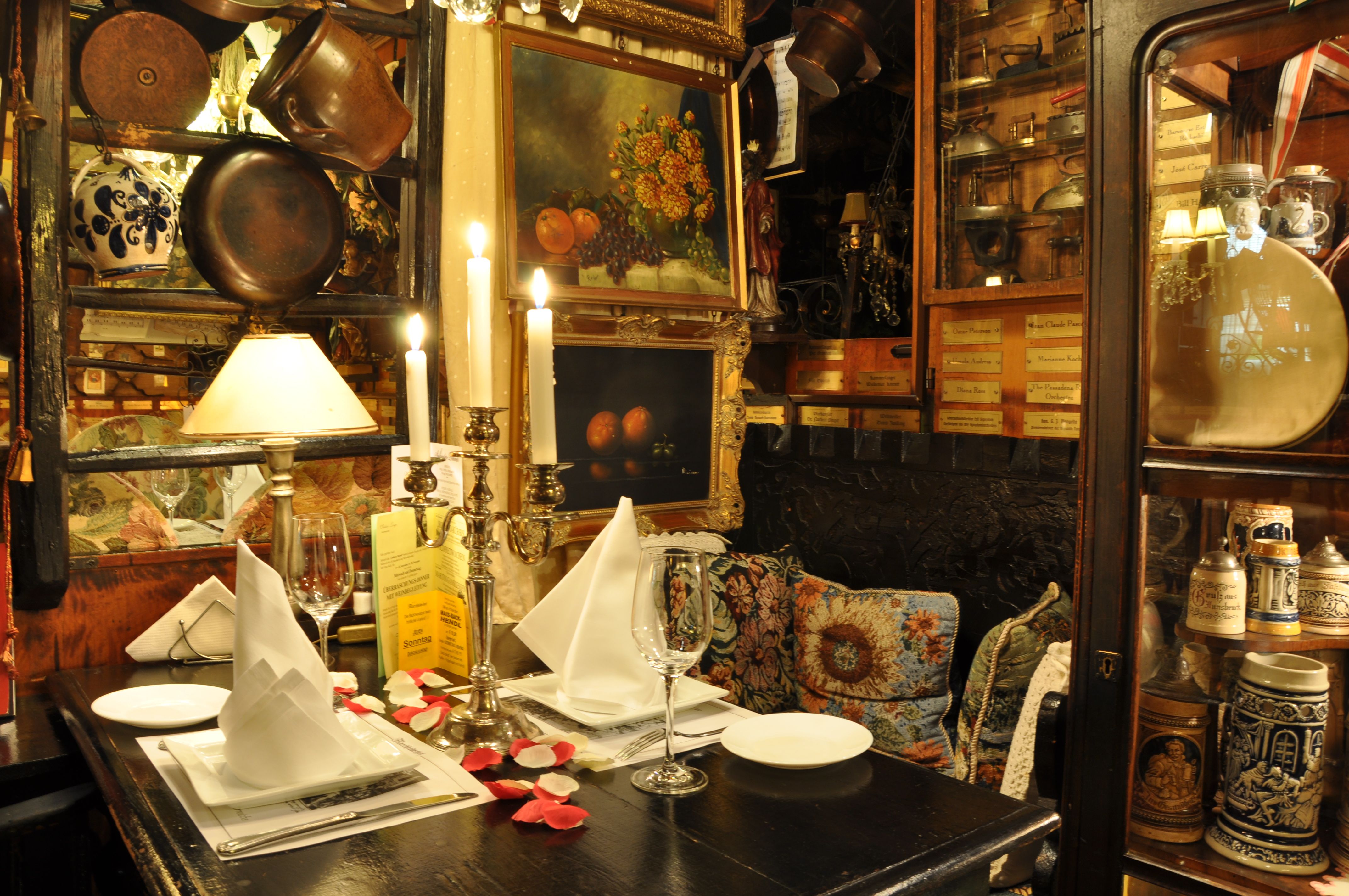 Hangulatosan díszített asztal egy rusztikus étteremben gyertyatartókkal, képekkel és antik tárgyakkal.