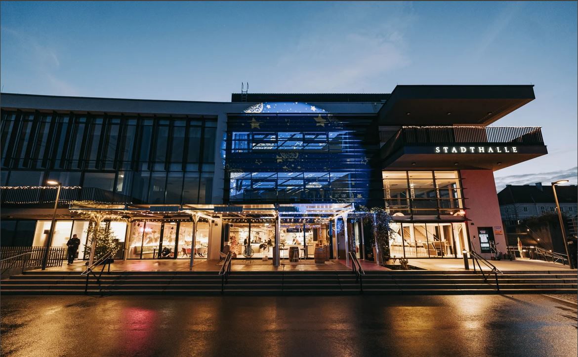 A Stadthalle Ybbs külső nézete alkonyatkor, kivilágított bejárattal.