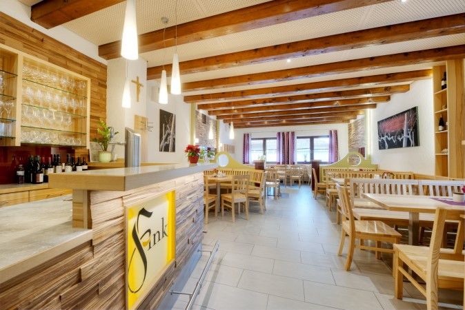 Belső nézet egy hangulatos, fából készült bútorokkal berendezett étkezőből és egy borozó stílusú bárból.