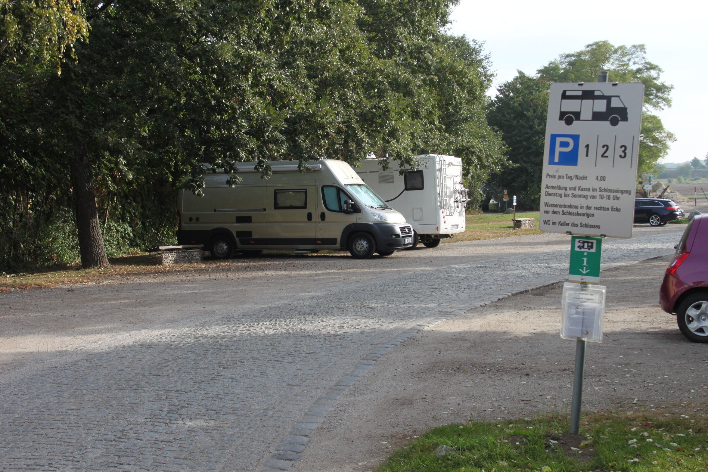 Lakóautó-parkolóhely két parkoló lakóautóval és egy útjelző táblával.