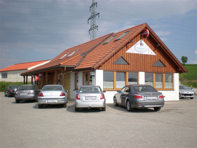 Egy étterem, fahomlokzatú étterem, előtte több parkoló autóval.
