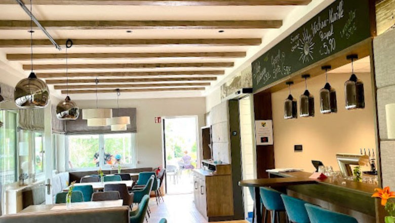 Belső &eacute;ttermi r&eacute;sz asztalokkal &eacute;s z&ouml;ld fotelekkel