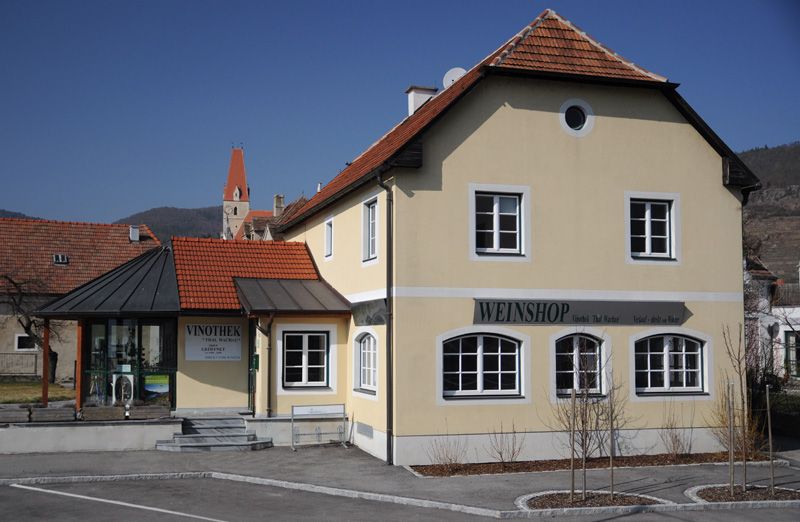 "Weinshop" és "Vinothek" feliratú sárga épület vidéki környezetben.