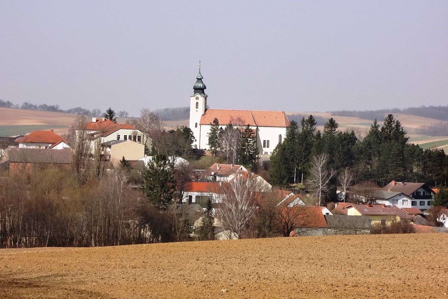 Gnadendorf falu látképe a templommal és a környező házakkal vidéki tájban.