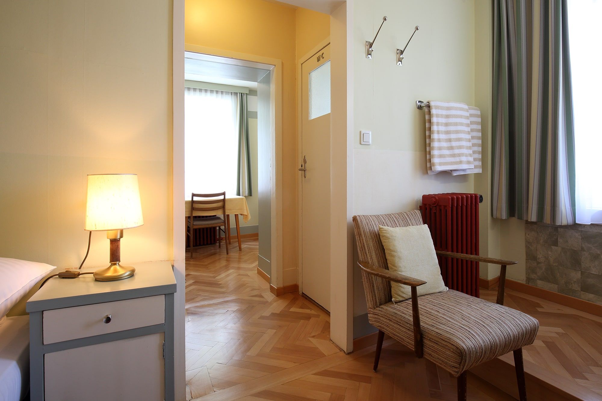 A Looshaus egyik szobájának belső nézete, a háttérben fotel, éjjeli lámpa és asztal.
