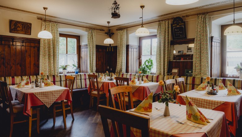 Hangulatos vendéglő fabútorokkal és kockás terítőkkel.