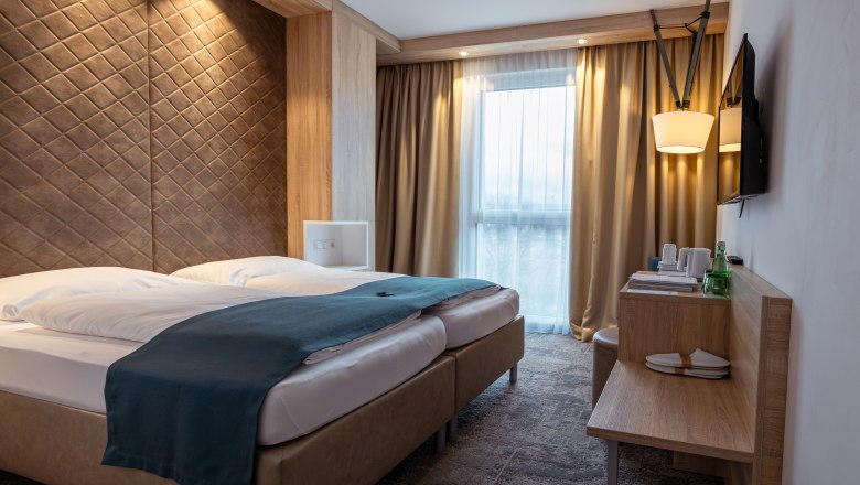 Modern sz&aacute;llodai szoba francia&aacute;ggyal, faburkolattal &eacute;s f&uuml;gg&ouml;ny&ouml;s ablakokkal.