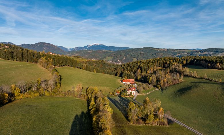 Tájkép St. Corona am Wechsel közelében, zöld dombokkal és egy tanyával.