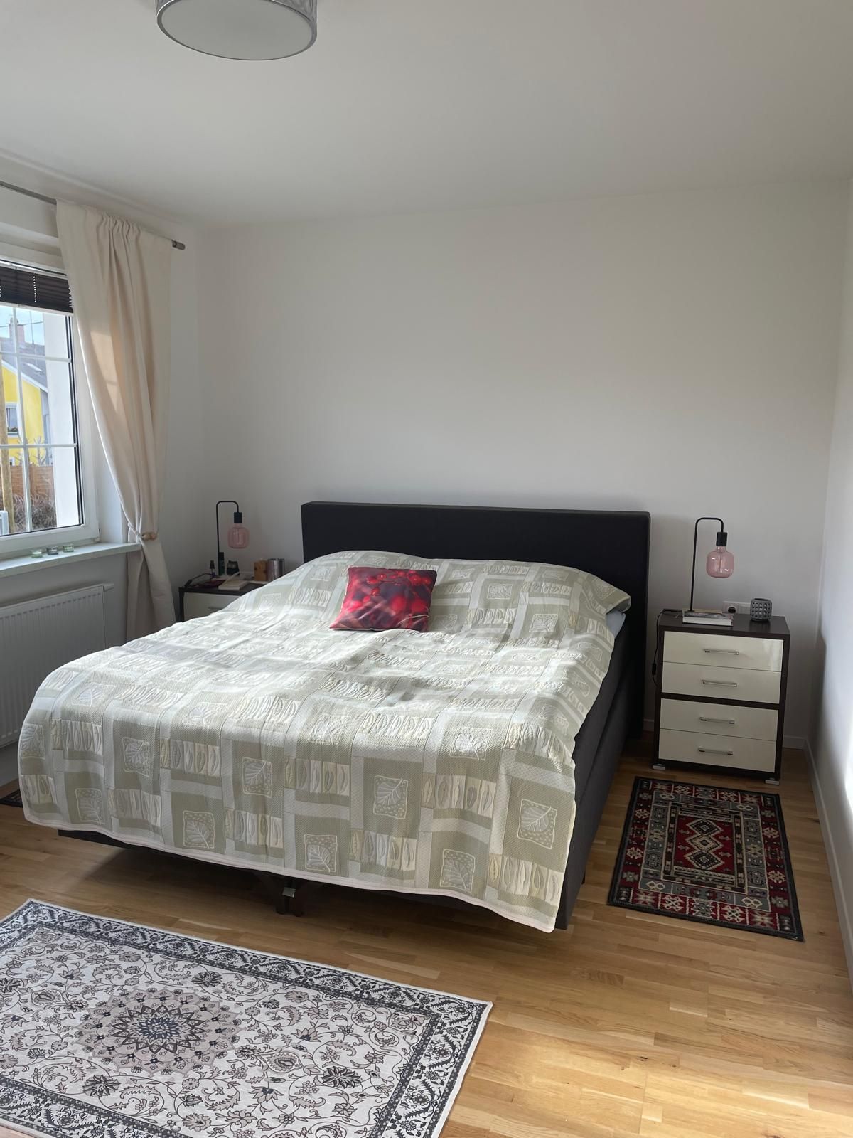 Egy hálószoba franciaággyal, két éjjeliszekrénnyel és szőnyegekkel, fapadlóval.