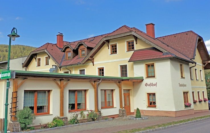 Hagyományos fogadó sárga homlokzattal és piros tetővel.