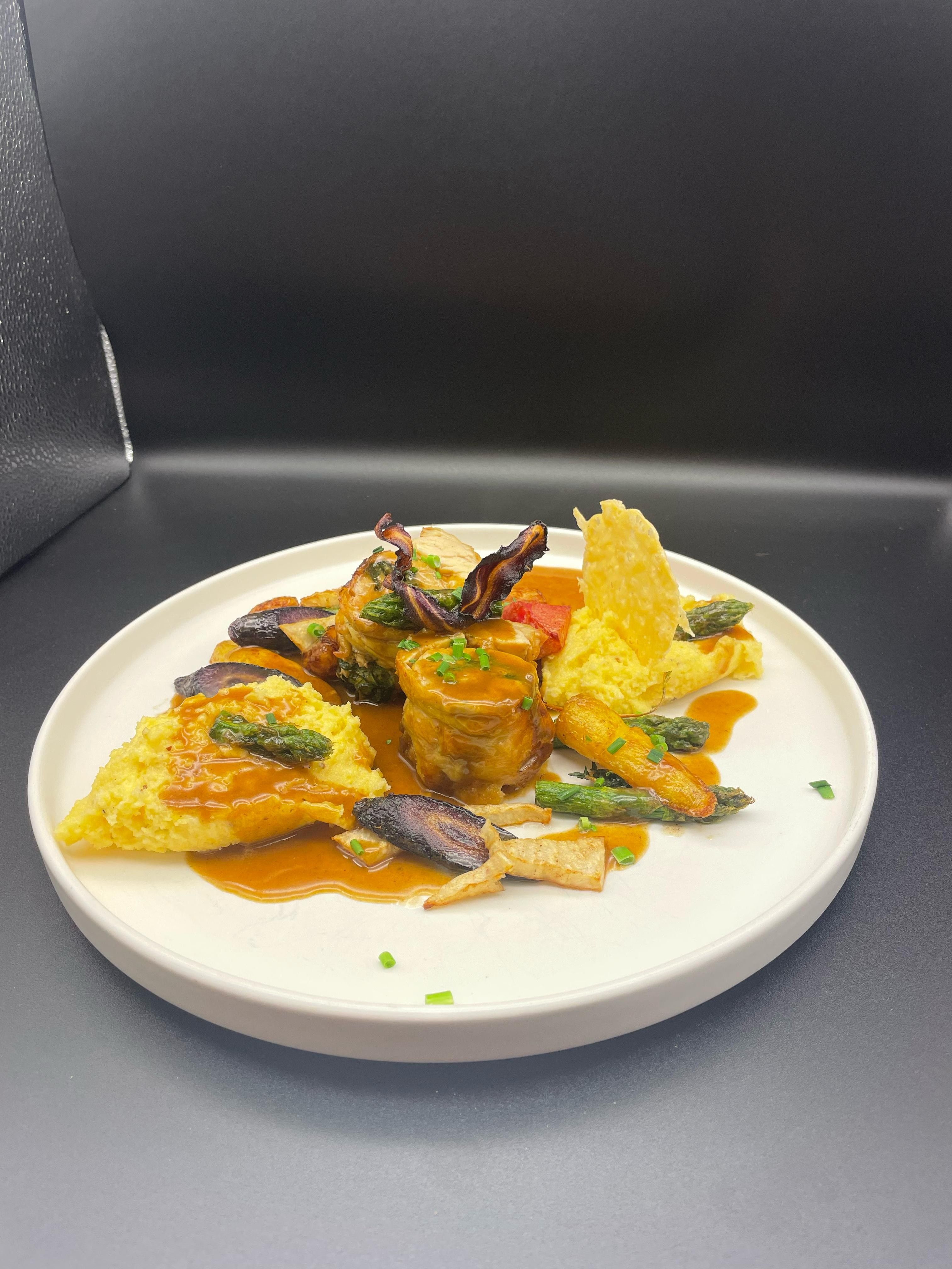 Ínyenc étel fehér tányéron hússal, zöldséggel és mártással.