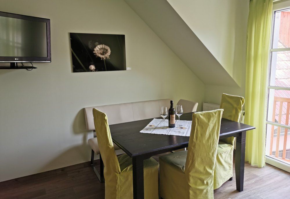 Étkező egy nyaraló apartmanban asztallal, székekkel és egy üveg borral.