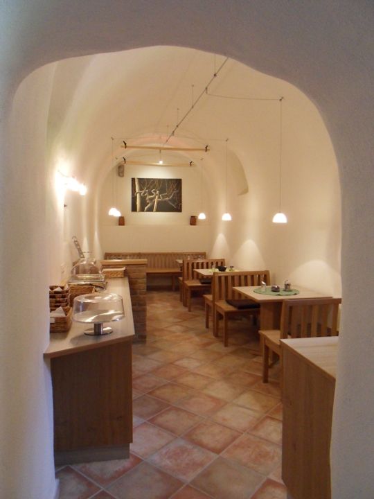 Hangulatos, fából készült bútorokkal és boltíves mennyezettel berendezett reggelizőterem.