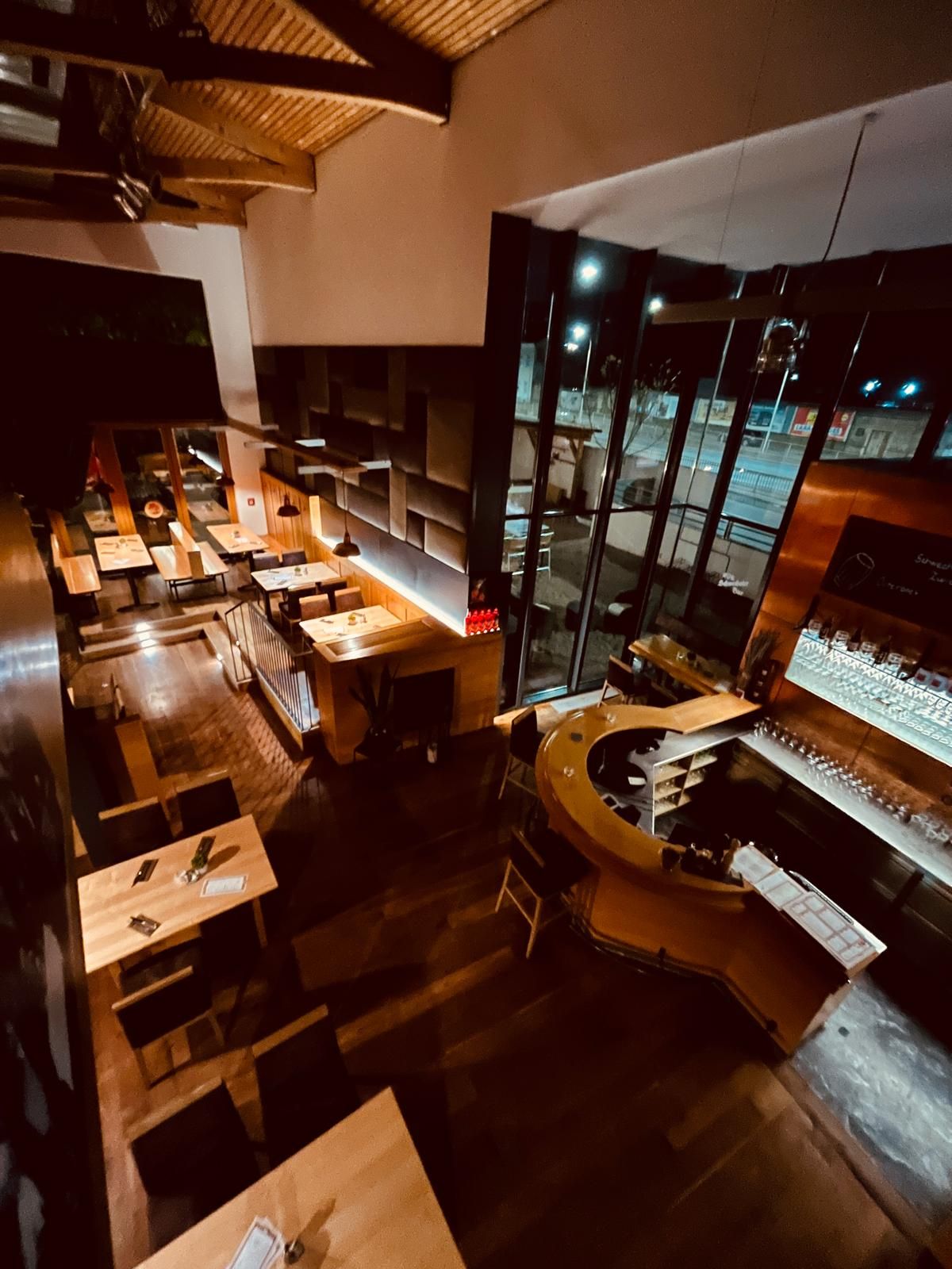 A Brauhaus Schwechat belső nézete éjszaka, faasztalokkal és bárpulttal.