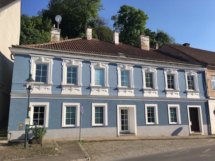 Kék színű történelmi épület fehér ablakkeretekkel és cseréptetővel.