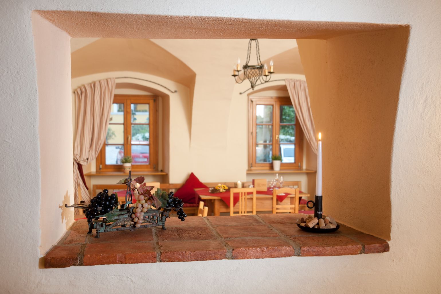 Kilátás a falon nyíló nyíláson keresztül egy hangulatos, fabútorokkal berendezett, gyertyafényes szobába.