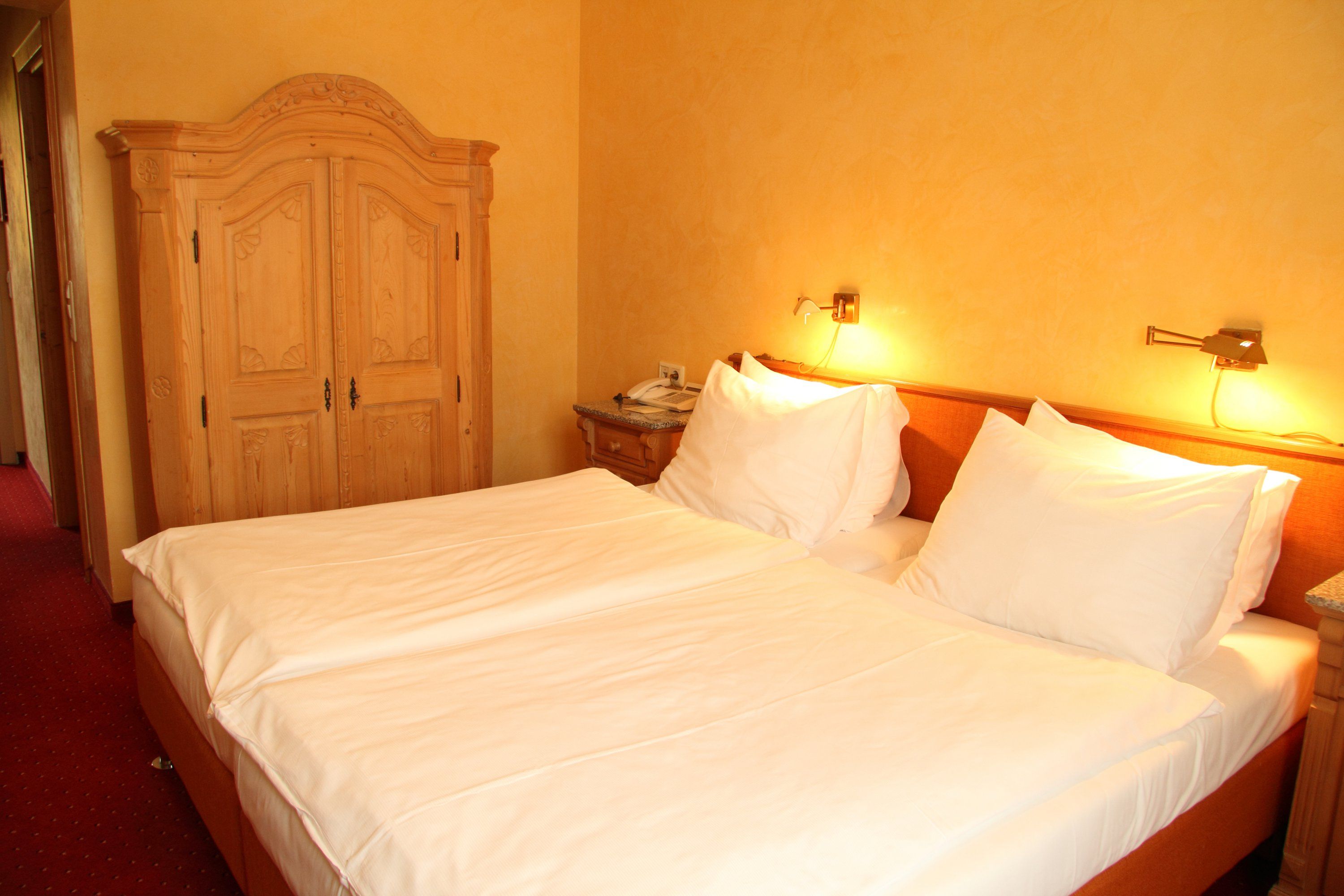 Hotelszoba franciaággyal, fabútorokkal és meleg fénnyel.