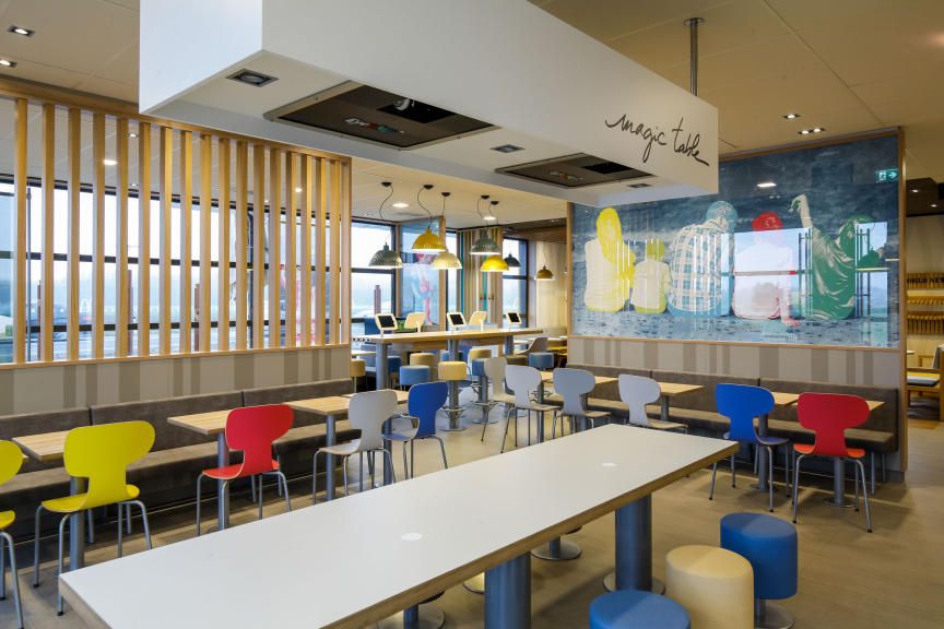 Egy modern McDonald's étterem belső nézete színes székekkel és asztalokkal.