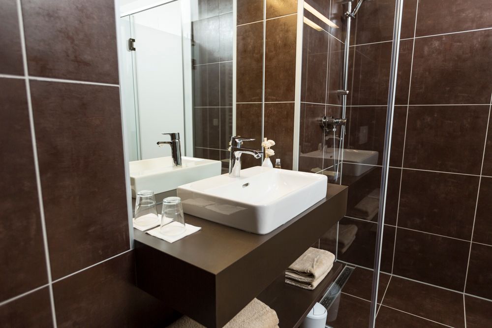 Modern fürdőszoba mosdóval, tükörrel és zuhanyzóval.