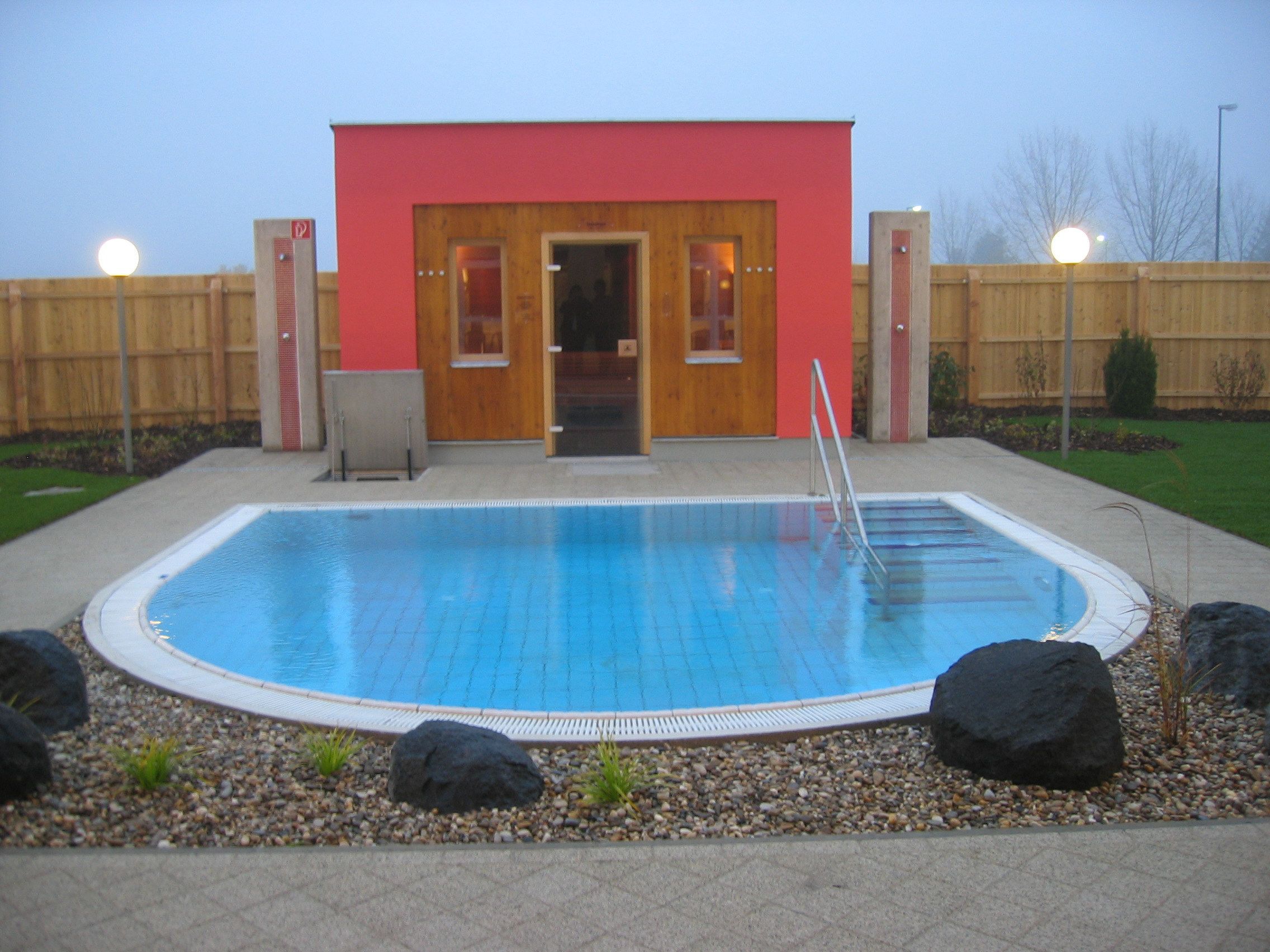 Külső nézet egy szaunára, kis medencével és kerttel.