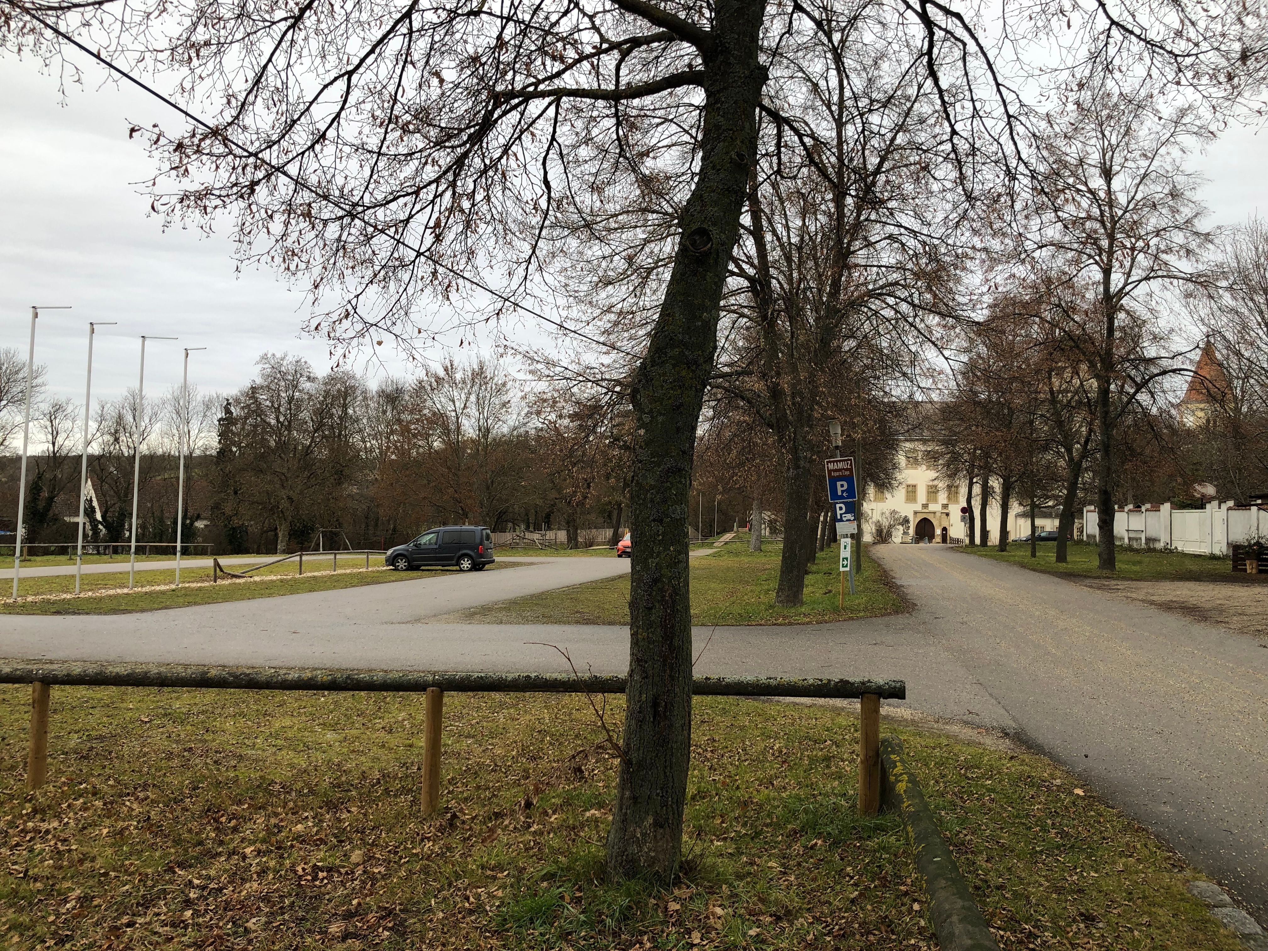 Parkoló, a háttérben fákkal és egy épülettel.