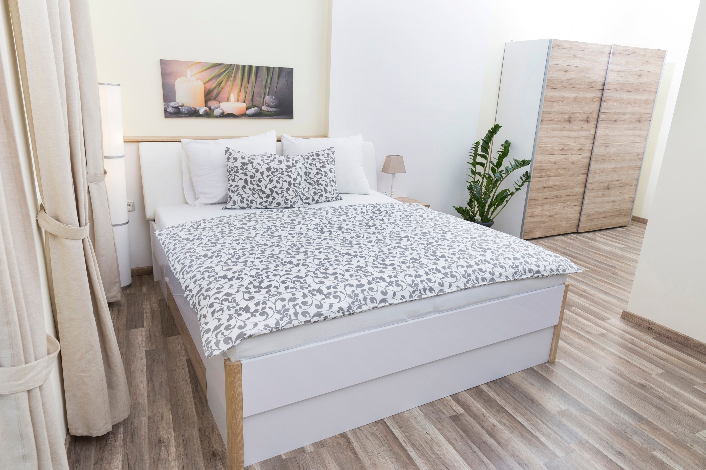 Modern hálószoba franciaággyal, növényekkel és szekrénnyel.