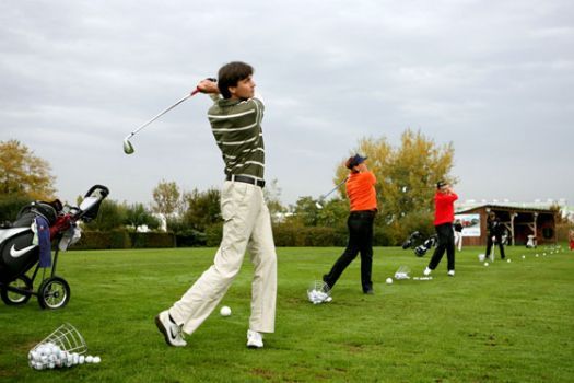 Emberek golfoznak egy golfpályán.