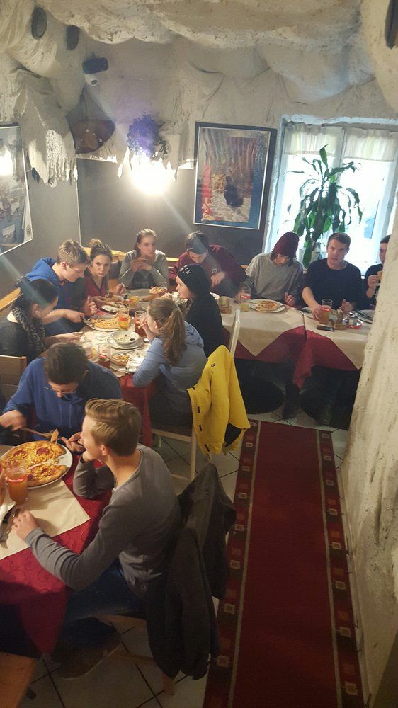 Emberek csoportja pizzát eszik egy hangulatos, barlangfalú étteremben.